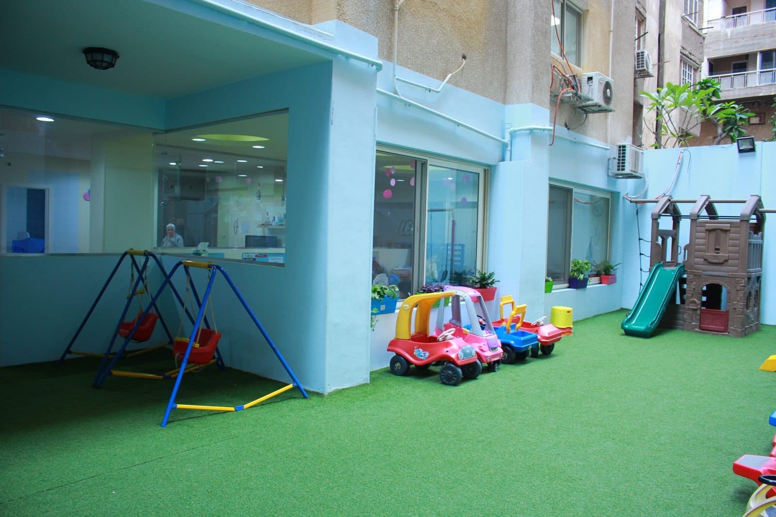 The garden with artificial grass, swings, ride-on cars and a climbing frame with a slide