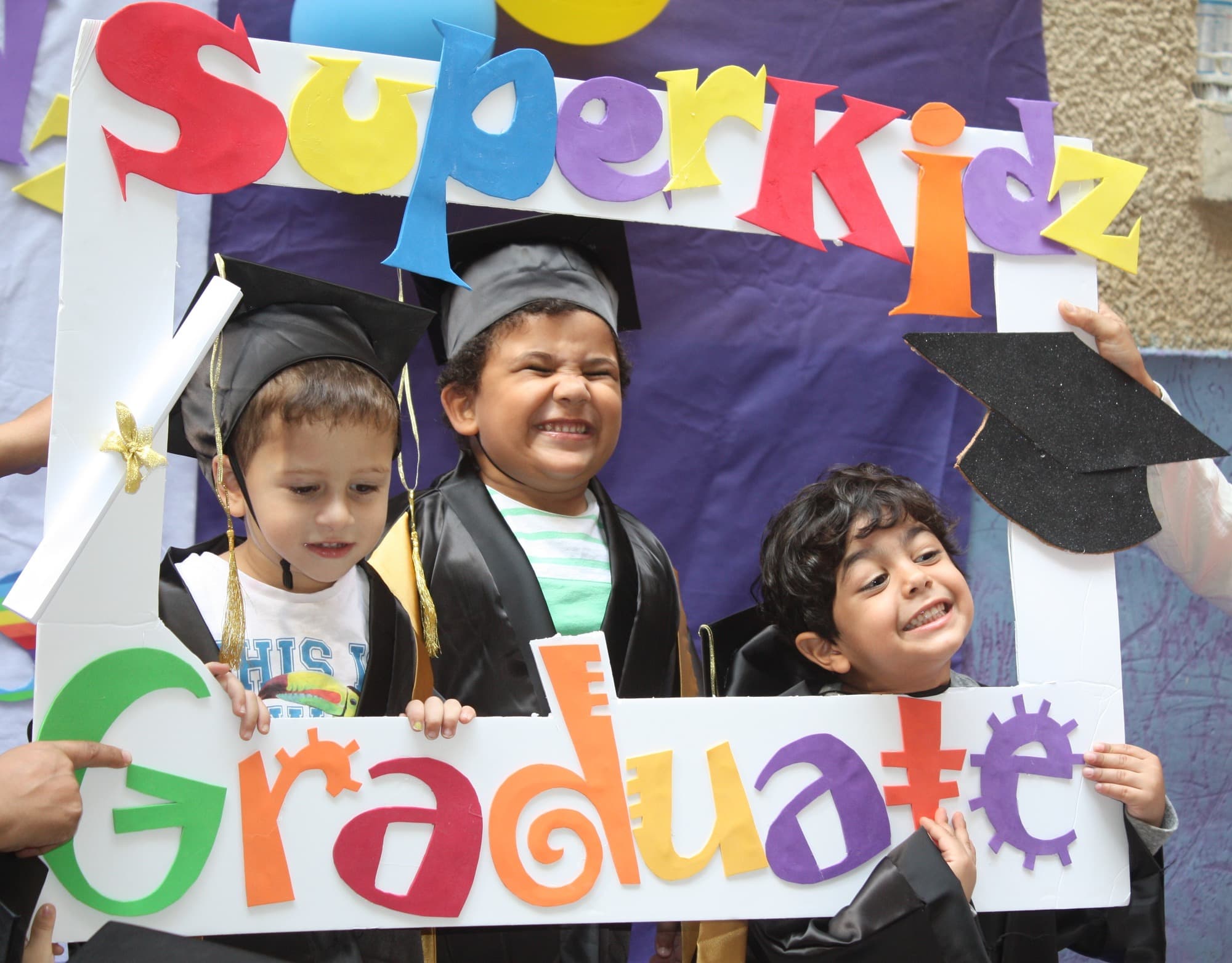A Super Kidz graduate celebrating in cap and gown