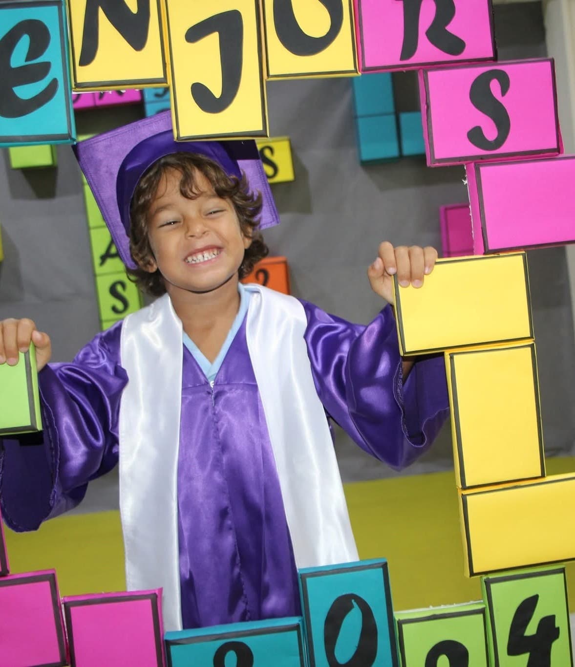 A Super Kidz graduate celebrating in cap and gown