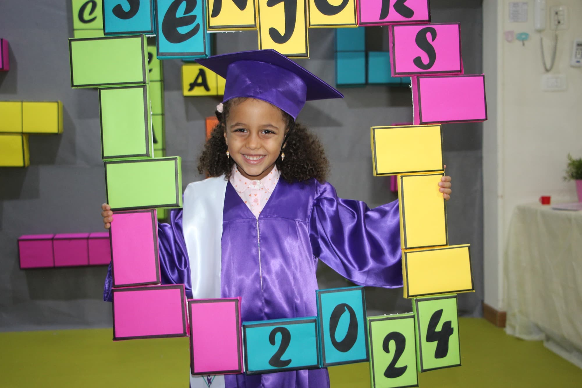 A Super Kidz graduate celebrating in cap and gown