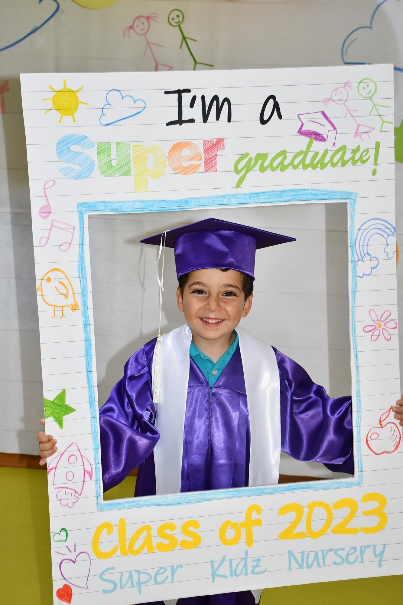 A Super Kidz graduate celebrating in cap and gown