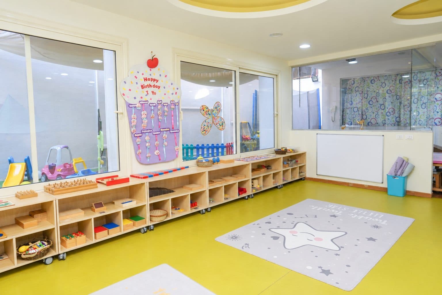 The Montessori corner, with low wooden shelves of Montessori materials along the windows