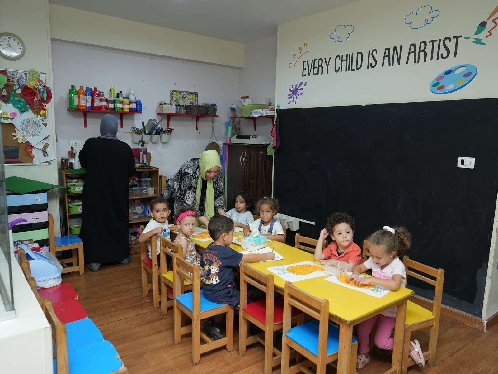 Children working at the art tables in the main room