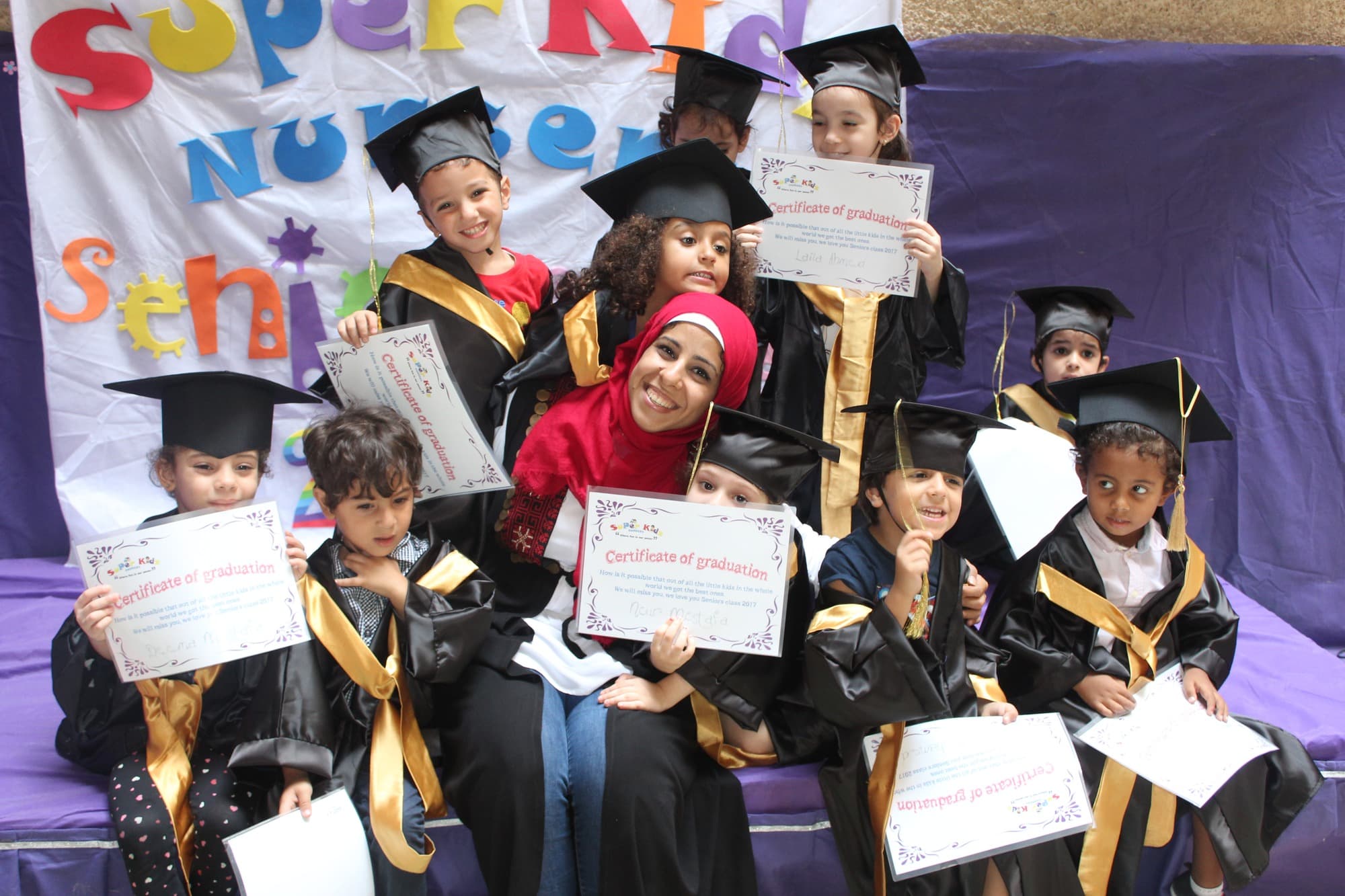 A Super Kidz graduating class posing together in caps and gowns