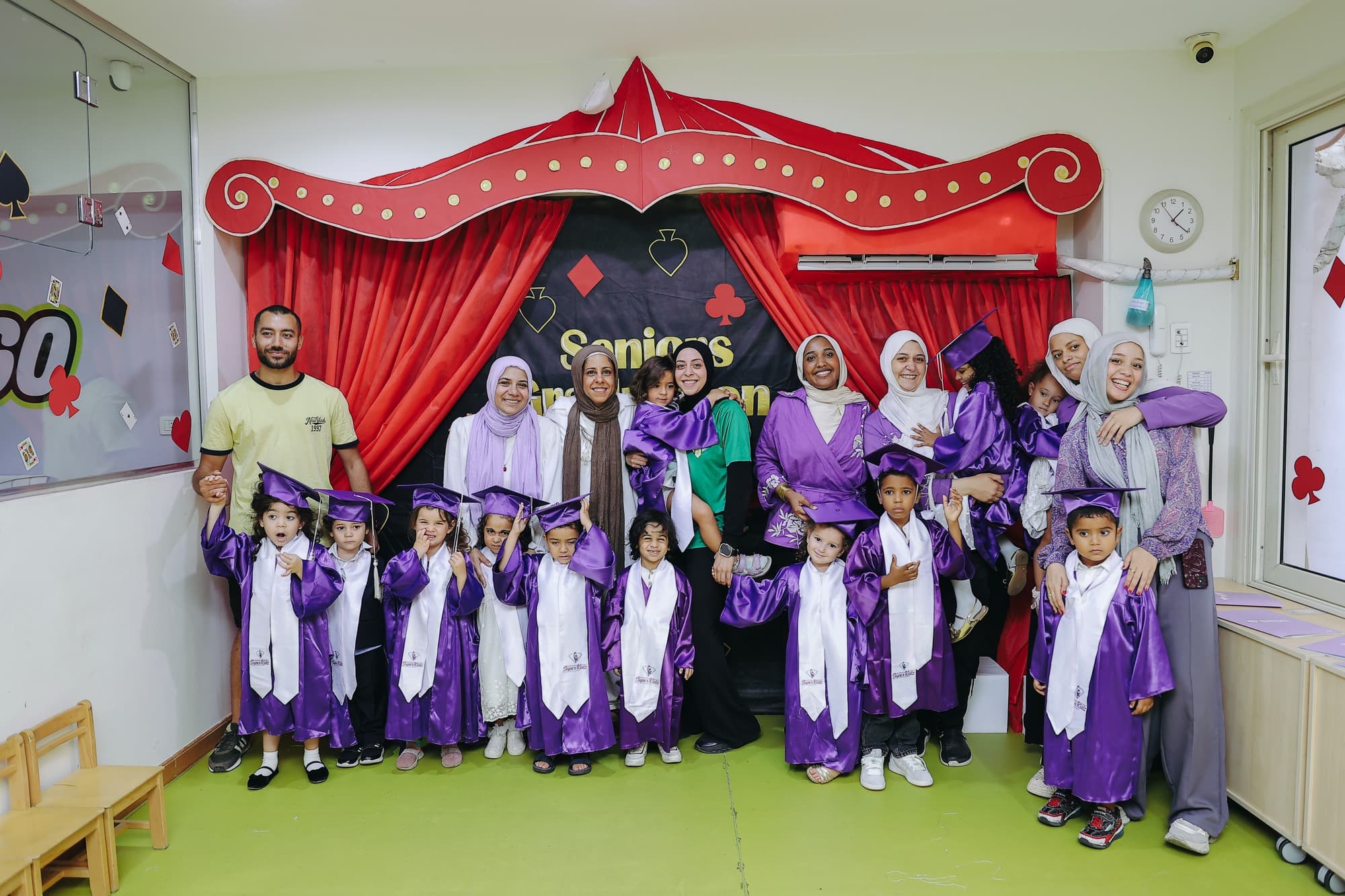 A Super Kidz graduating class posing together in caps and gowns