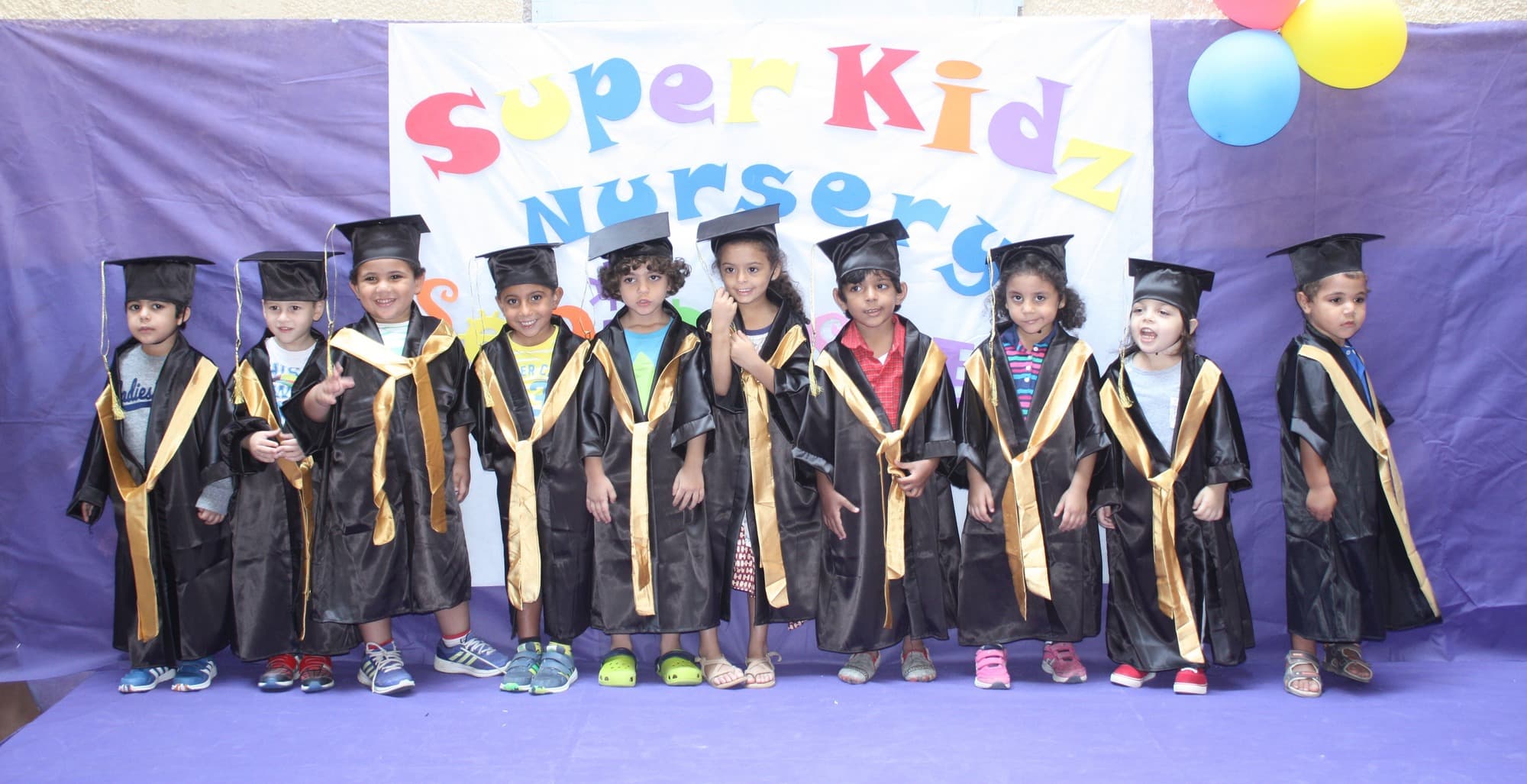 A Super Kidz graduating class posing together in caps and gowns