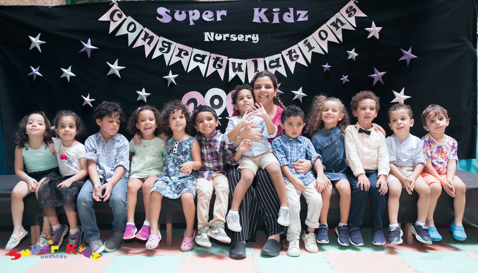 A Super Kidz graduating class posing together in caps and gowns