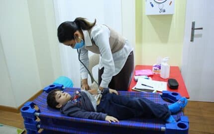A visiting doctor examining a child during the weekly health check